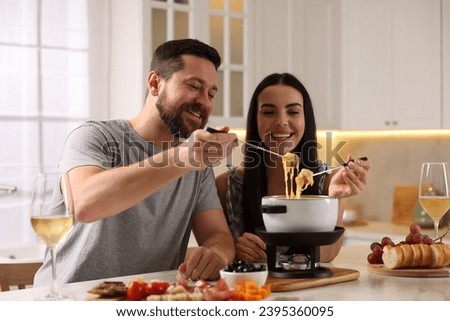 Affectionate couple enjoying cheese fondue during romantic date in kitchen