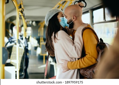 Affectionate Couple With Face Masks Kissing While Commuting By Bus. 