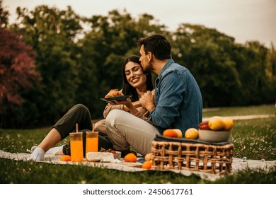 Affectionate couple laughing and enjoying snacks during a picnic outing - Powered by Shutterstock