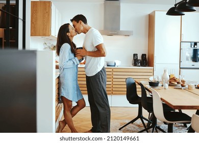 Affectionate couple in pajamas kissing each other in their kitchen at home in the morning - Powered by Shutterstock