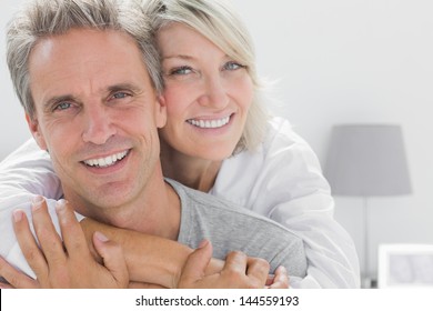 Affectionate couple smiling at camera at home in bedroom - Powered by Shutterstock