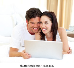 Affectionate couple using laptop lying on the bed