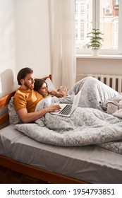 Affectionate couple using laptop while lying on the bed at the morning at home