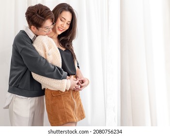 Affectionate Gay Women Couple Standing Holding Hands Embracing Each Other Smile. Beautiful Same Sex Young Married Asian Lesbians Couple Stay Home Together Enjoy Sweet Romantic Moment Relationship