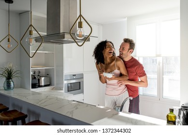 Affectionate interracial couple kissing while having healthy breakfast at home in the kitchen - Powered by Shutterstock