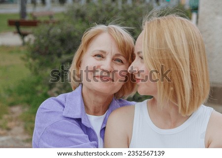 Affectionate loving middle-aged mother hugs an adult child. Glad to see daughter, happy elderly mother hugging her, sitting together in nature.