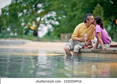 Affectionate Mature Couple Relaxing Poolside With A Glass Of Wine.