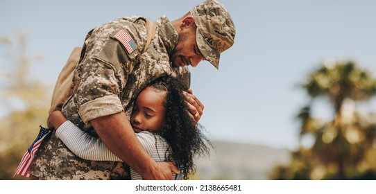 Affectionate military reunion between father and daughter. Emotional military dad embracing his daughter on his homecoming. Army soldier receiving a warm welcome from his child after deployment. - Powered by Shutterstock