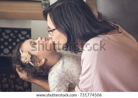 Affectionate mother and daughter bonding and enjoying in time together. Mother is kissing small girl on chin.