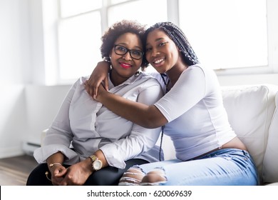 A affectionate mother and daughter sitting on sofa