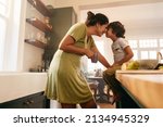 Affectionate mother touching noses with her young son in the kitchen. Cheerful mother and son looking at each other fondly. Loving single mother bonding with her son at home.