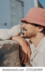 Affectionate Nose Rub Between a Man in a Bucket Hat and a White Cat.