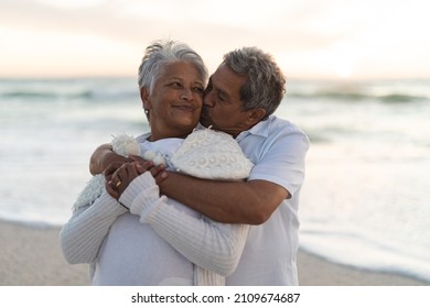 Affectionate senior biracial man kissing while hugging woman from behind at beach during sunset. lifestyle, love and weekend. - Powered by Shutterstock