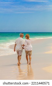 Affectionate senior Caucasian couple in casual clothing walking by ocean waves on tropical beach at remote destination Bahamas - Shutterstock ID 2211440571