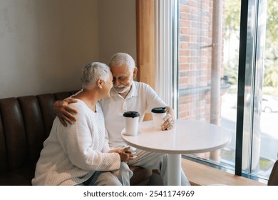 Affectionate senior couple enjoying each other company having coffee at cafe, loving bond evident in embrace, loving looking at each other. Happy retirement life filled with leisure, togetherness - Powered by Shutterstock