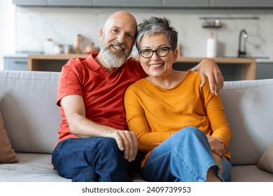 Affectionate senior couple sitting on comfortable sofa and embracing, loving elderly spouses smiling at camera, reflecting happy life at home, relaxing together in living room interior, closeup - Powered by Shutterstock