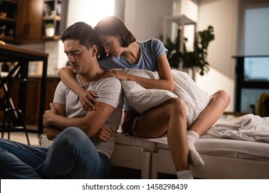 Affectionate woman embracing her sad boyfriend and consoling him after the argument in the bedroom. 