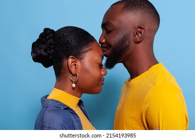 Affectionate woman in love kissing boyfriend on forehead in studio. Girlfriend expressing feelings and affection, showing fondness and appreciation with kiss for partner. Romantic gesture