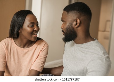 Affectionate young African American couple talking together while sitting in their pajamas on their bed in the morning - Shutterstock ID 1511797187