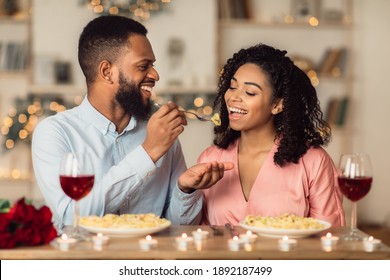 Affectionate Young Black Couple Having Dinner, Guy Feeding His Girlfriend With Pasta. Cute Lovers Having Romantic Date, Flirting, Having Fun, Celebrating St Valentine's Day Or Holiday