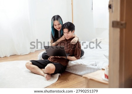 Affectionate Young Couple Bonding While Watching Laptop on Floor in Bedrooom