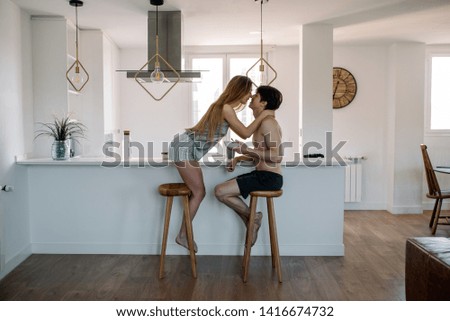 Affectionate young couple cuddling while having healthy breakfast at home in the kitchen