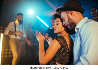 An affectionate young couple dancing on a crowded dance floor in a nightclub