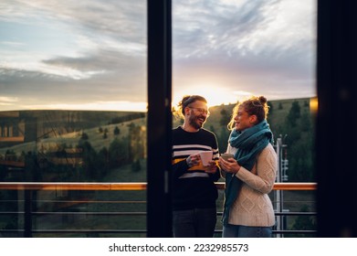 Affectionate young couple drinking coffee or tea while standing on their balcony at home in the morning with a beautiful nature view. Watching the sunrise with a romantic partner. Copy space. - Shutterstock ID 2232985573