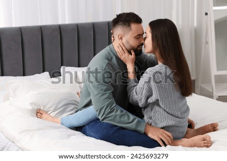 Affectionate young couple kissing in bedroom. Space for text