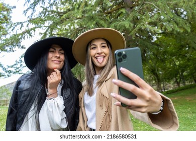 Affectionate Young Couple Taking A Self-portrait With A Smartphone At The Park. Teenage Womans Outdoors Taking Their Picture With Mobile Phone.