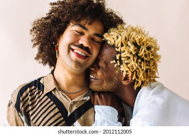 Affectionate young gay couple embracing each other while standing together in a studio. Two young male lovers smiling cheerfully while posing against a studio background. Gay couple being romantic. - Powered by Shutterstock