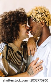 Affectionate Young Gay Couple Touching Their Noses Together In A Studio. Two Young Male Lovers Posing With Their Eyes Closed Against A Studio Background. Young Gay Couple Being Romantic.