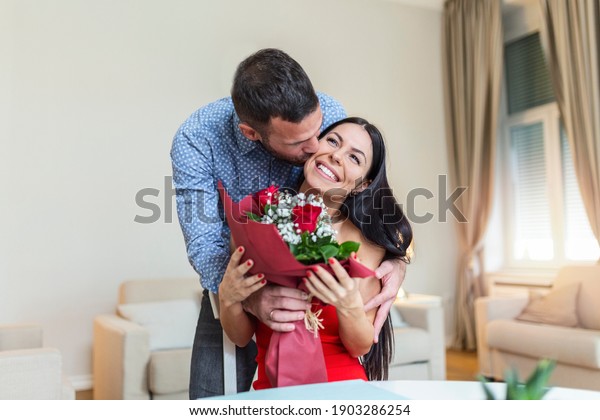 Affectionate young man giving his beautiful young wife a bouquet of red ... pic