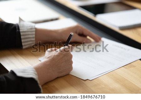 Affirming contract. Close up of businesswoman female executive ceo boss sitting at office desk signing order investment agreement insurance policy closing deal confirming paper document approving sale
