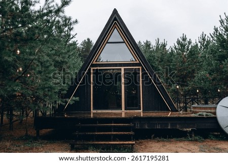 a-frame house in forest, cozy triangular shaped house for guests and tourists, glamping concept