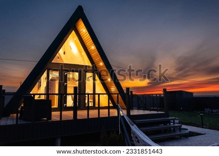 a-frame house in Scandinavian style on the background of the sunset sky. Landscape. rest in the country in the evening