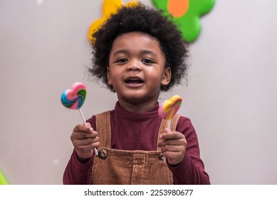 Africa American boy hold on colourful candy in Kids birthday celebratiion party. - Shutterstock ID 2253980677