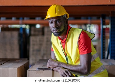 Africa American Engineer Man Wearing Safety Helmet And Vest Standing In The Automotive Part Warehouse. Looking At Camera Portrait Of Worker. Logistic And Business Export At Distribution Center