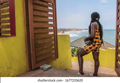 Africa Woman Looks Out Over The City Of Accra In Ghana. The Sea And The Background Of The Independence Arch.