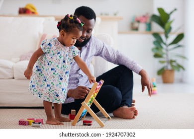 africam american family, father and daughter playing with wooden abacus and toys at home - Powered by Shutterstock