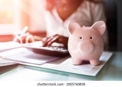 African Accounting Tax Advisor Using Calculator And Piggy Bank