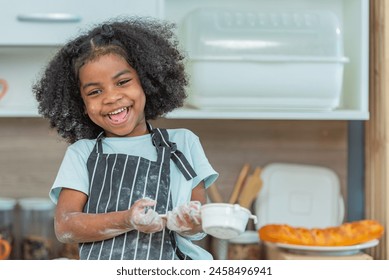 african afro black daughter kids sifting flour powder and sprinkling ingredients on massaging dough for bakery cooking. Black african daughter afro hair enjoy sifting flour wheat by sieve in kitchen - Powered by Shutterstock