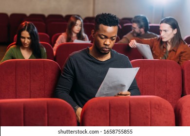 african american actor reading screenplay on seats in theatre