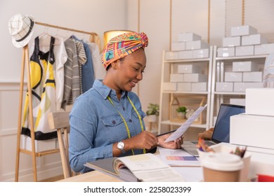 African american adult female woman fashion designer cloth tailor creative working for new collection.Happy online store owner preparing an order for shipping . - Shutterstock ID 2258023399