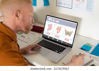African american albino businessman researching on nfts while working on laptop in office. Unaltered, business, wireless technology, finance, non fungible tokens, occupation and office concept.