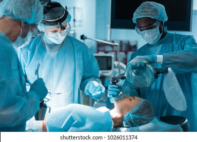 african american anesthetist holding oxygen mask above patient in operating room - Powered by Shutterstock