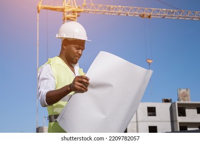 African American architect compares building construction to drawings of future project. Black constructor controls building at back sunlight - Powered by Shutterstock