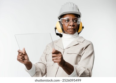 African American architect woman in safety gear holding a clear sheet smart construction technology. African American architect woman, smart construction technology. Smart construction technology, - Powered by Shutterstock