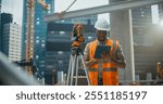 African American Architect Working as a Civil Engineer. Young Black Man Using Optical Total Station Theodolite for Planning and Surveying the Construction of a Commercial Real Estate Building