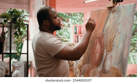 African american artist using watercolor paint and mixing colors on palette for his artistic creation in fine art workshop. Man painting rustic elements on canvas, creative process. Camera A. - Powered by Shutterstock